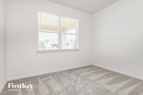 a bedroom with a window and a carpeted floor