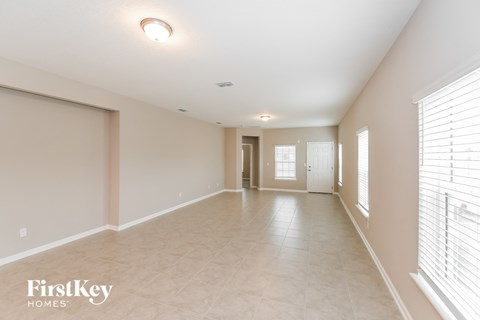 a spacious living room with a large window and a tiled floor