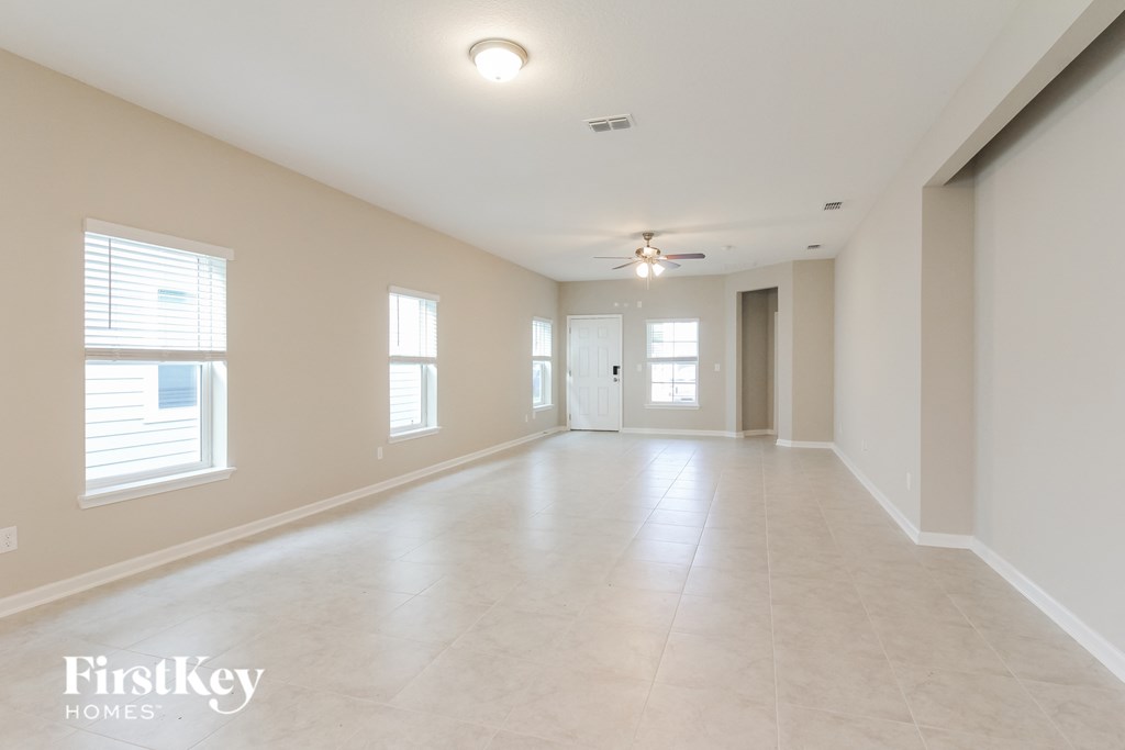 an empty living room with windows and a ceiling fan