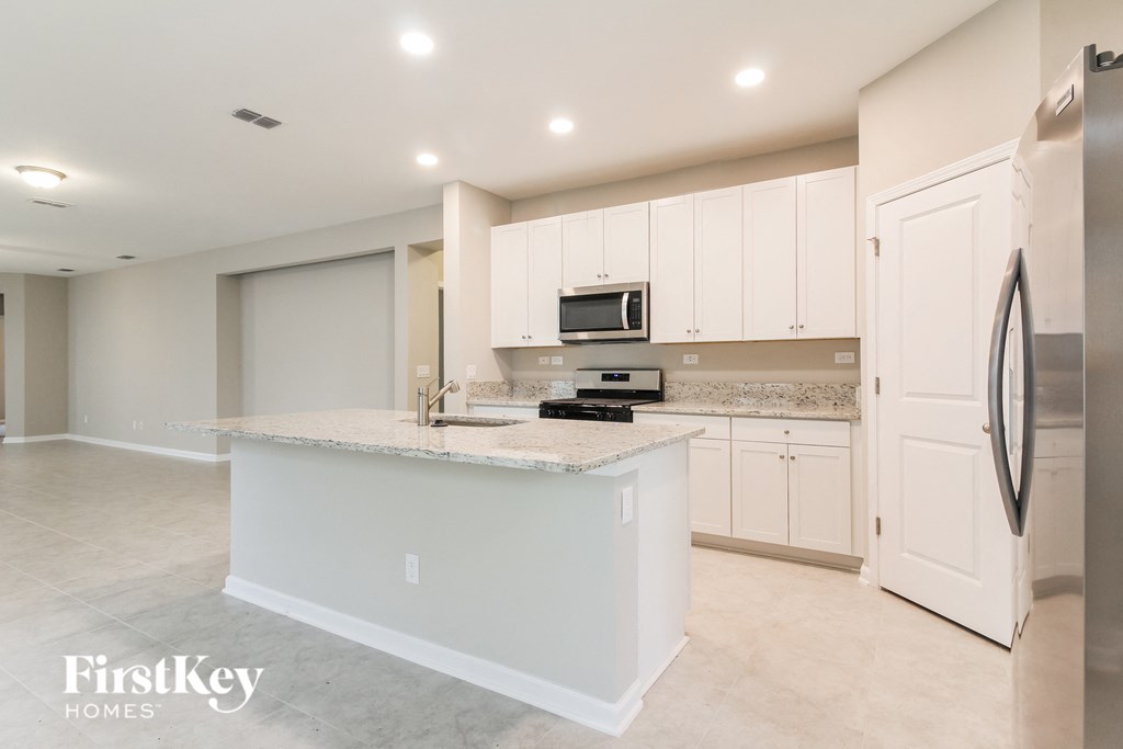 a large kitchen with white cabinets and a marble counter top