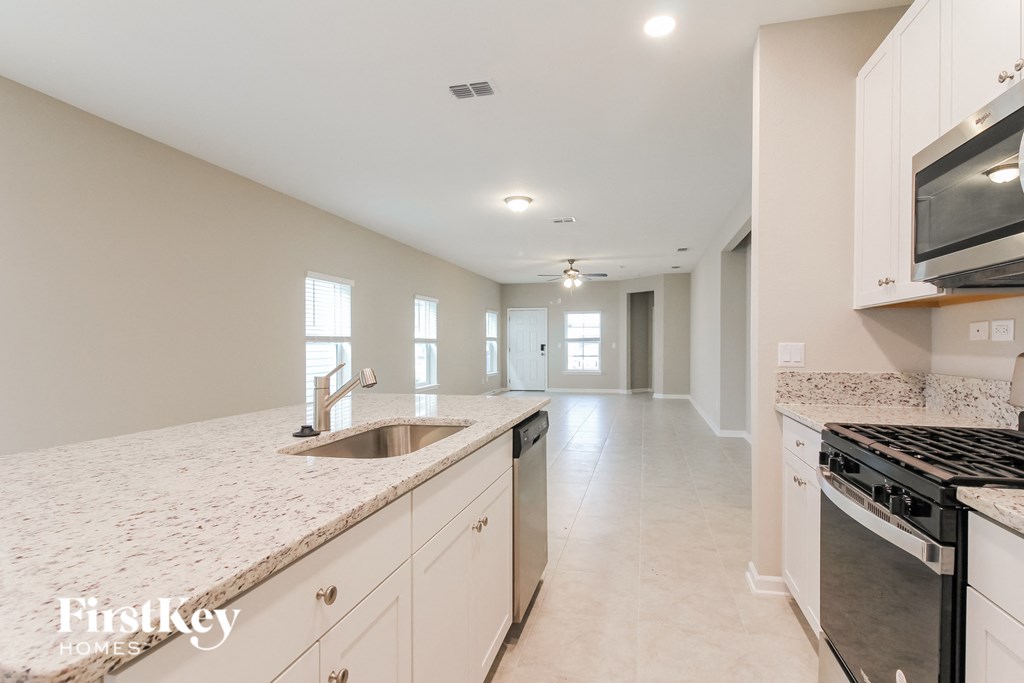a kitchen with white cabinets and granite counter tops and a stove and a sink
