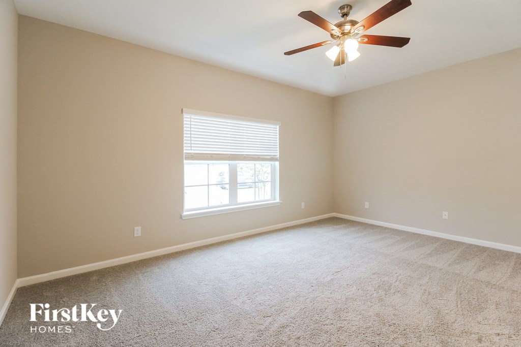 an empty living room with a ceiling fan and a window