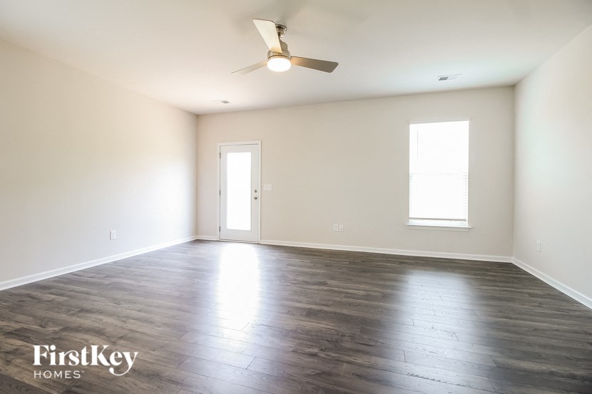 an empty living room with wood floors and a ceiling fan