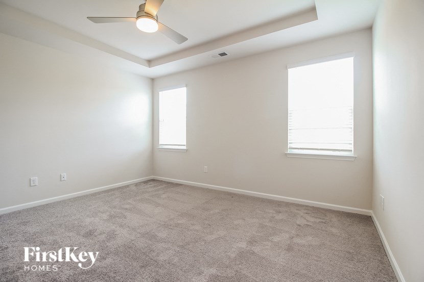 a empty room with a ceiling fan and two windows