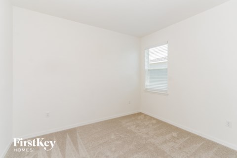 a bedroom with white walls and carpet and a window