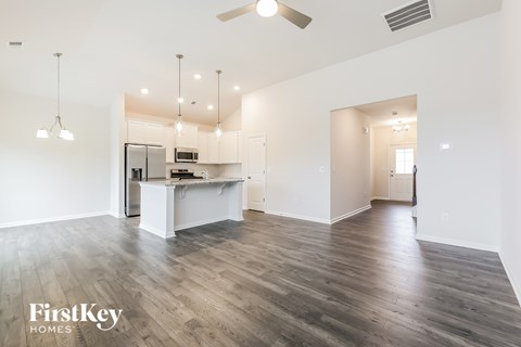 A spacious kitchen and living room with wooden flooring and a ceiling fan.