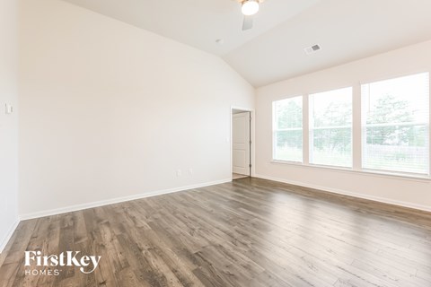 A spacious room with wooden flooring and a ceiling fan.