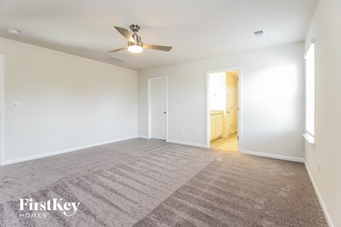a spacious living room with carpet and a ceiling fan