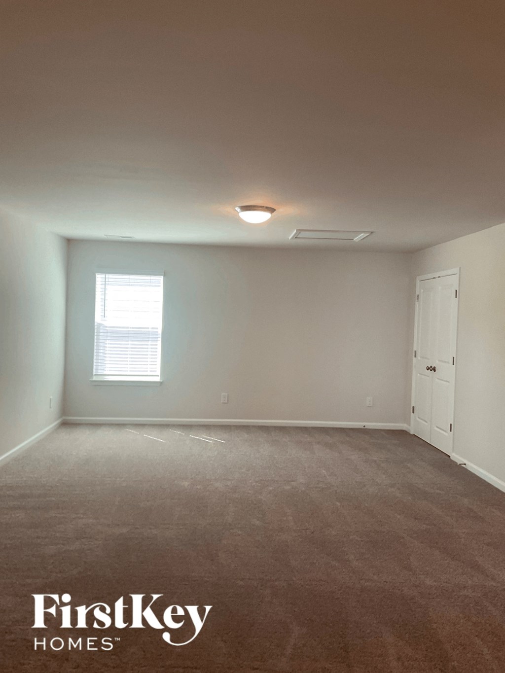 an empty living room with white walls and a window