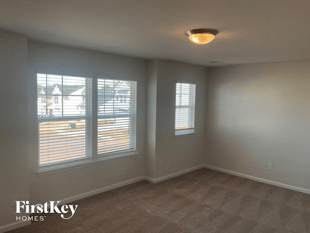 an empty room with three windows and a carpeted floor