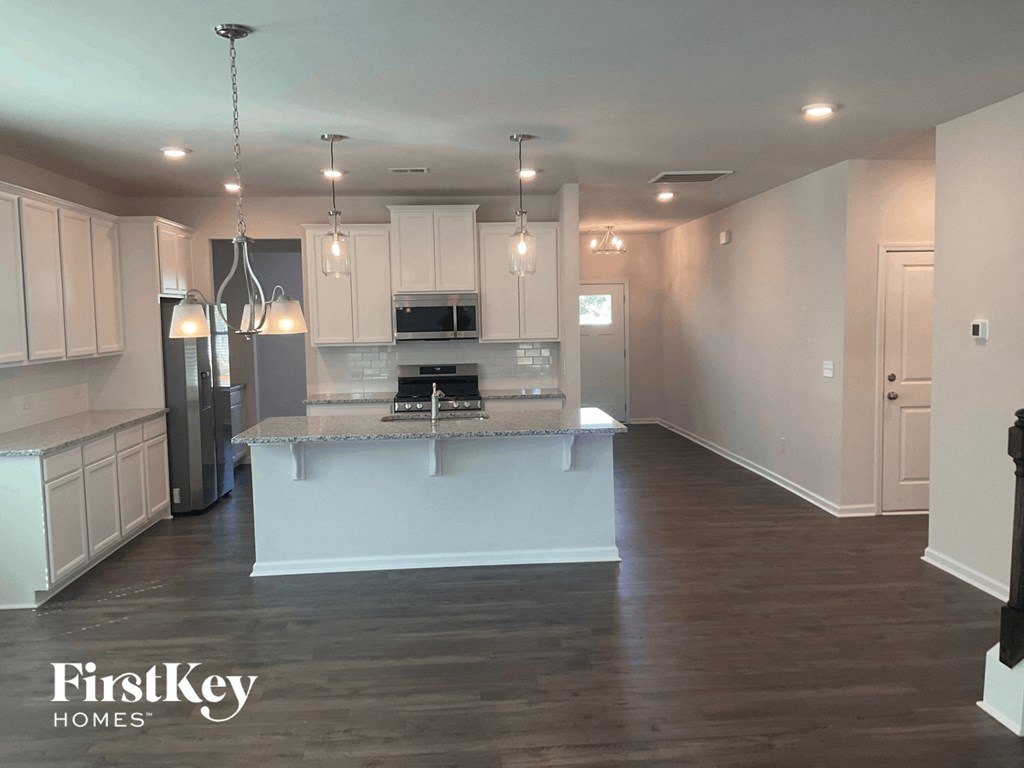 an open kitchen with white cabinets and a marble counter top