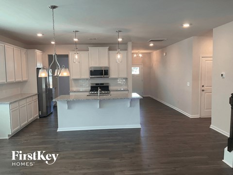 an open kitchen with white cabinets and a marble counter top