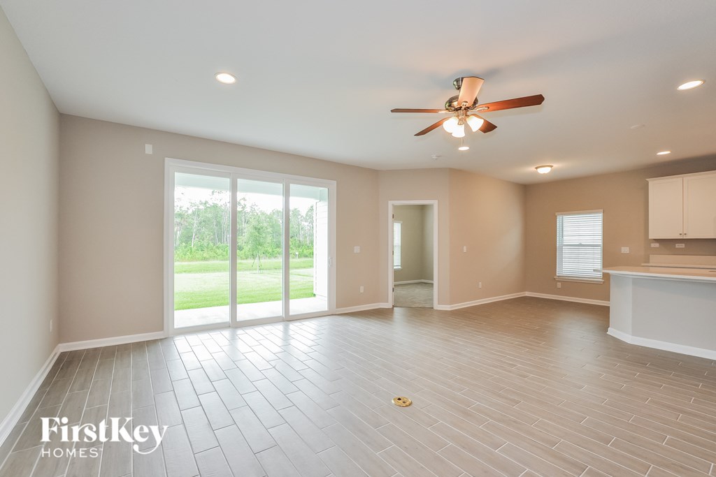 an empty living room with a ceiling fan and sliding glass doors
