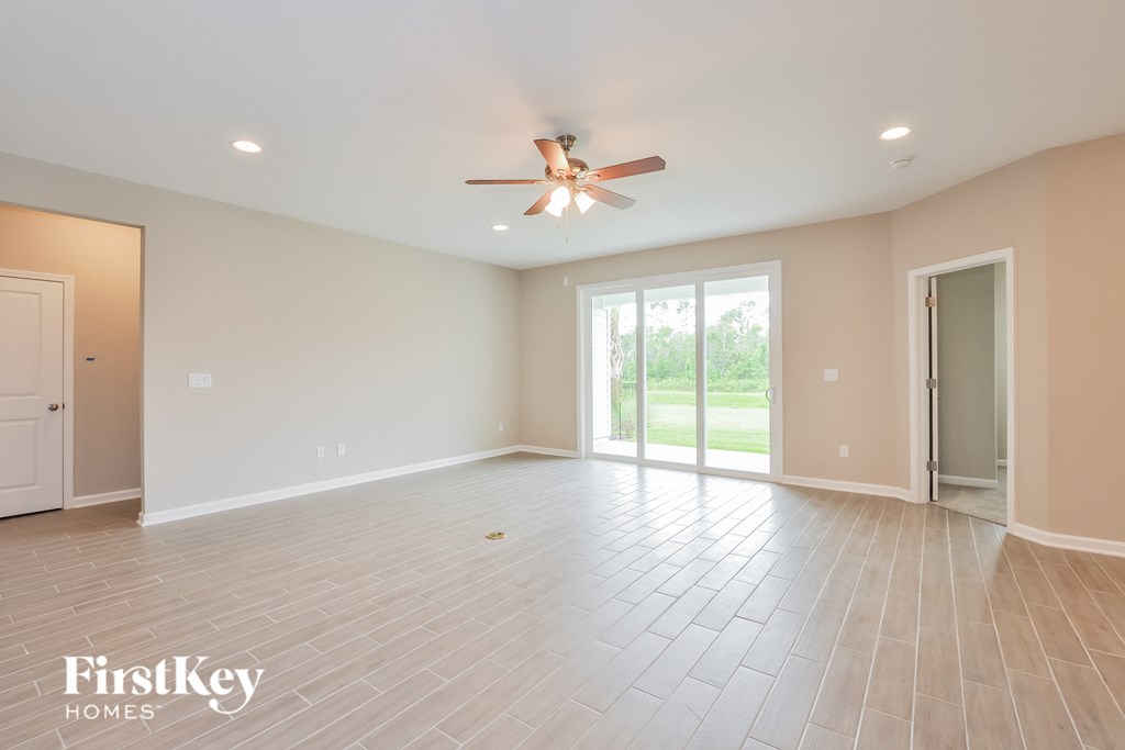 an empty living room with a ceiling fan and a sliding glass door
