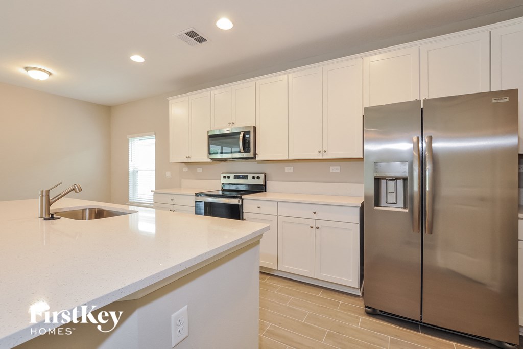 a white kitchen with stainless steel appliances and white counter tops