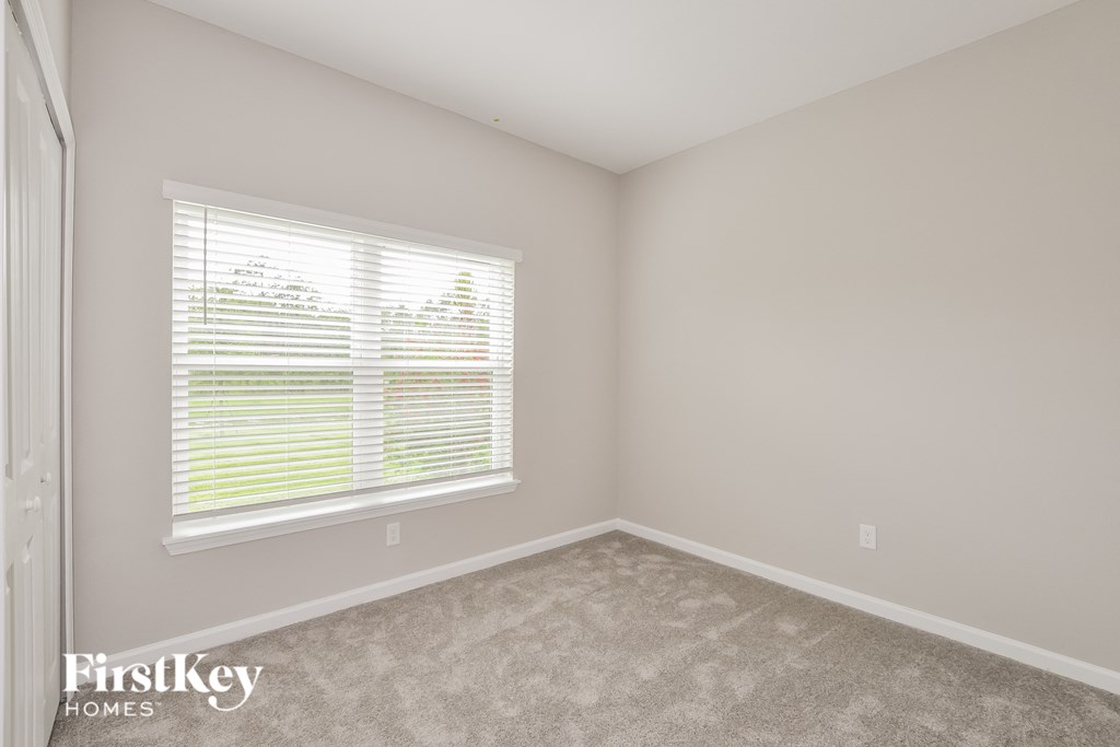 a bedroom with a large window and a carpeted floor