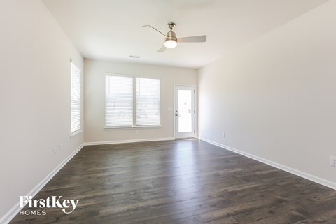 A spacious room with wooden floors and a ceiling fan.