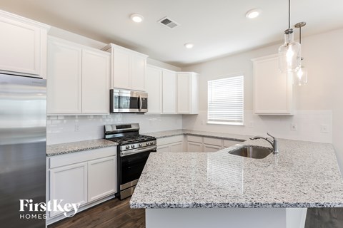 A kitchen with granite countertops and white cabinets.