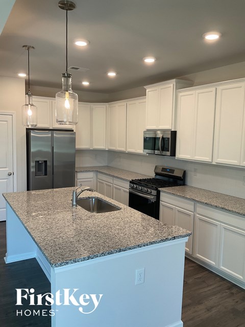 A kitchen with granite countertops and white cabinets.