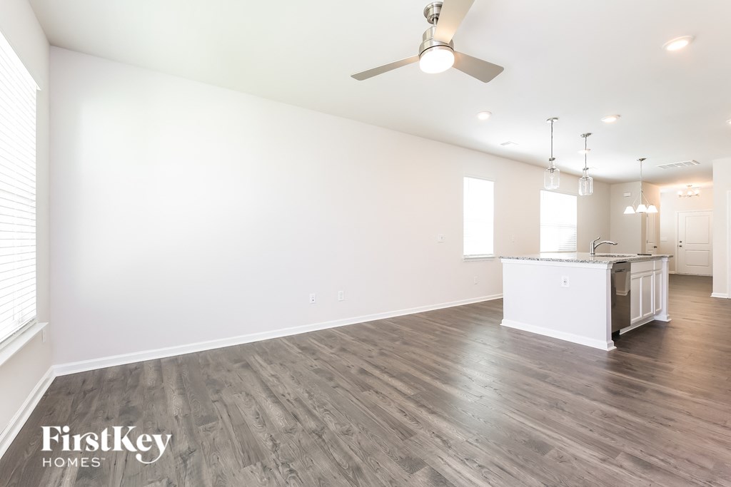 the living room and kitchen of a new home with white walls and wood flooring