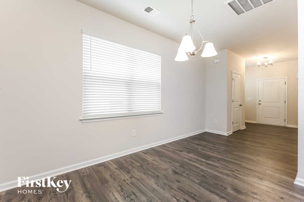 the living room and dining room of an apartment with wood flooring and a window