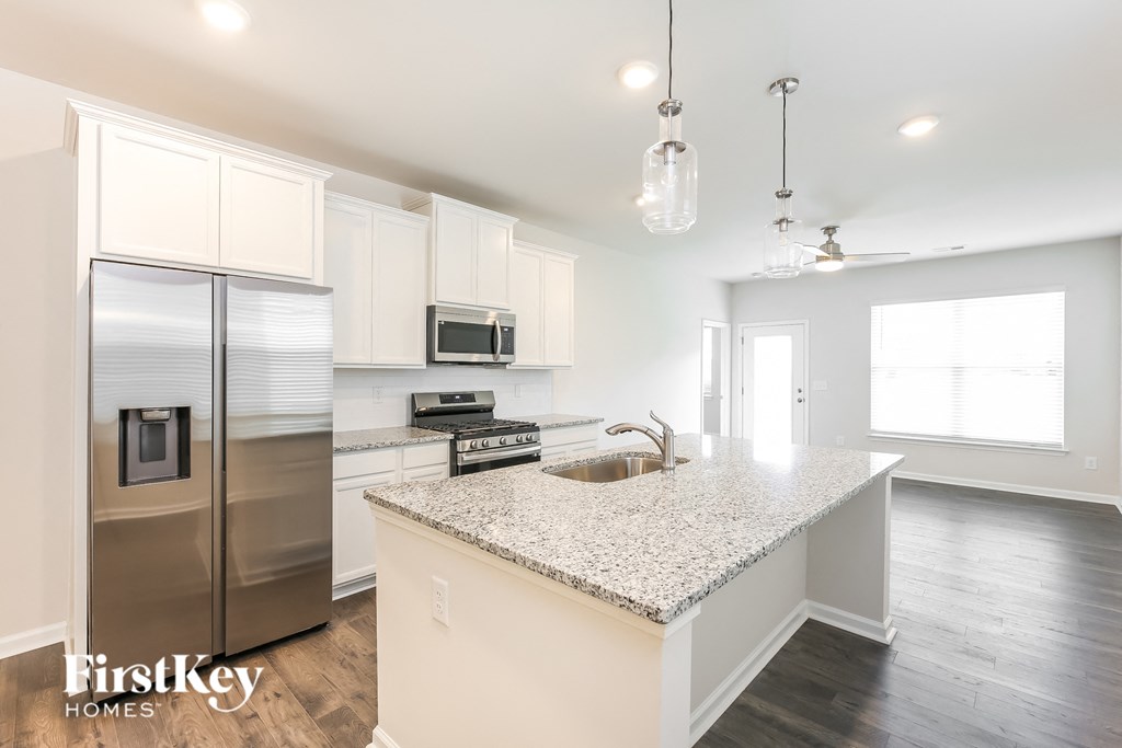 a white kitchen with stainless steel appliances and a granite counter top