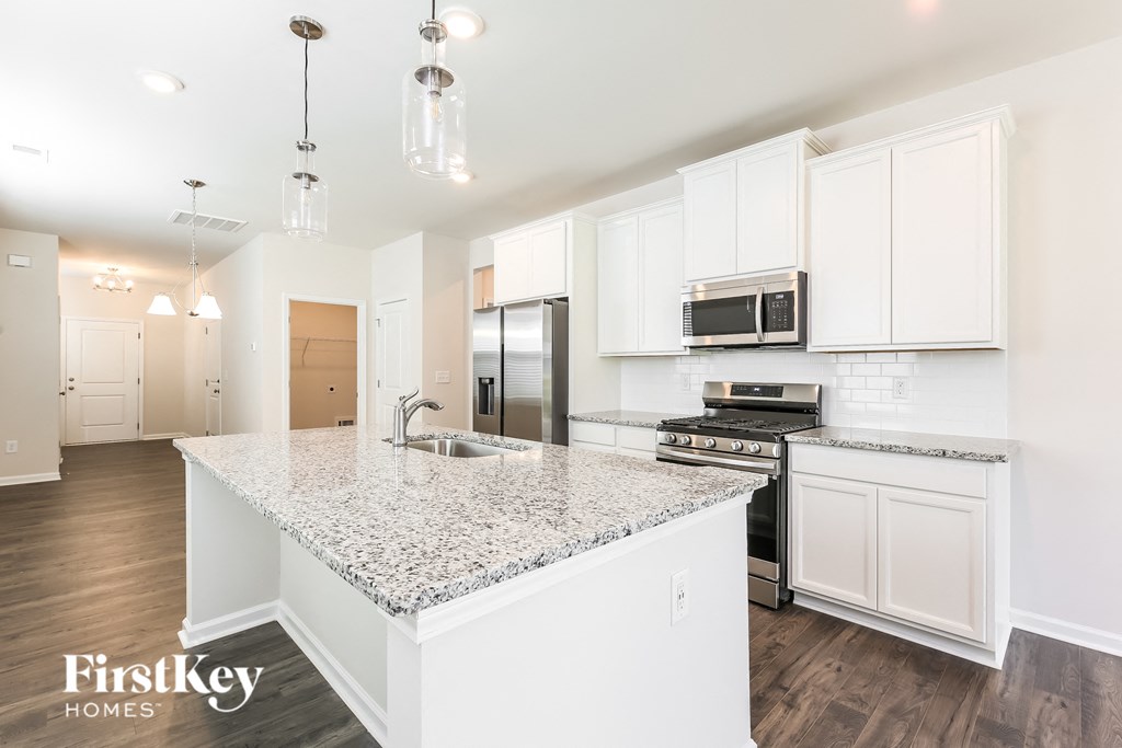 a kitchen with white cabinets and a marble counter top