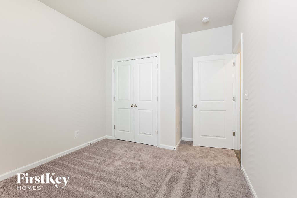 a bedroom with two doors and a carpeted floor
