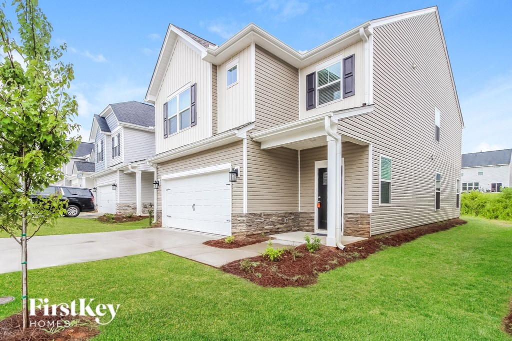 A house with a garage and a tree in front of it.