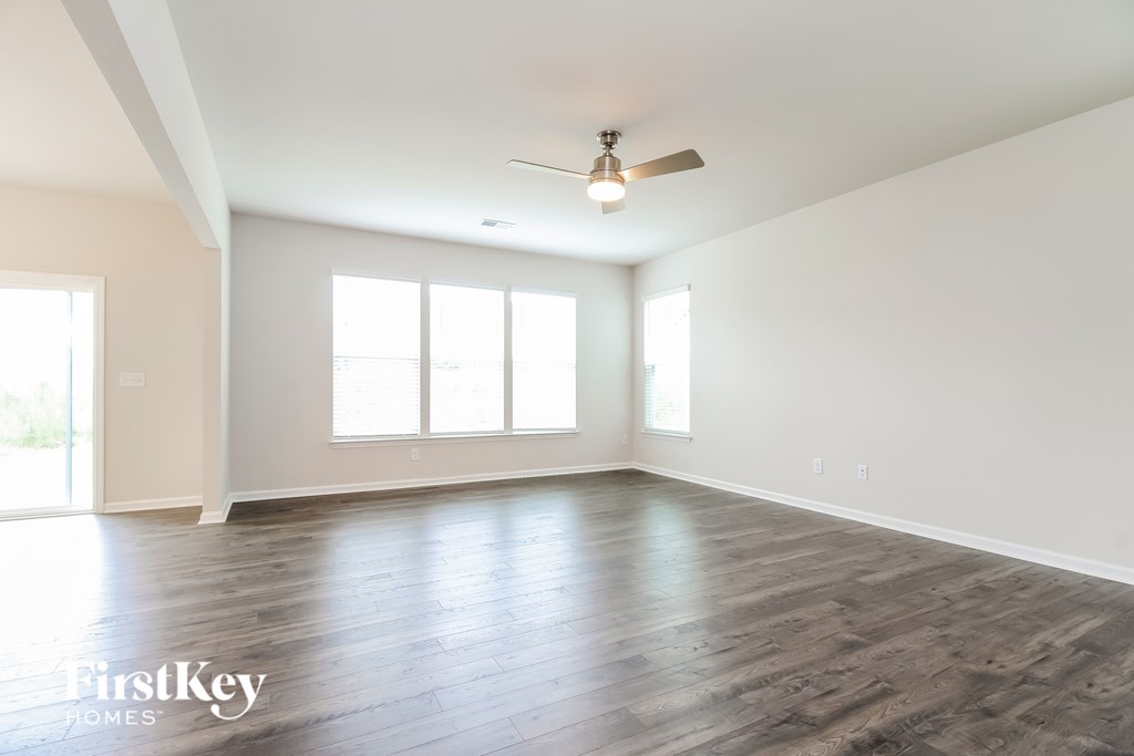 A spacious room with a ceiling fan and large windows.