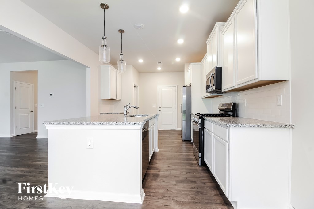 A kitchen with white cabinets and a marble island.