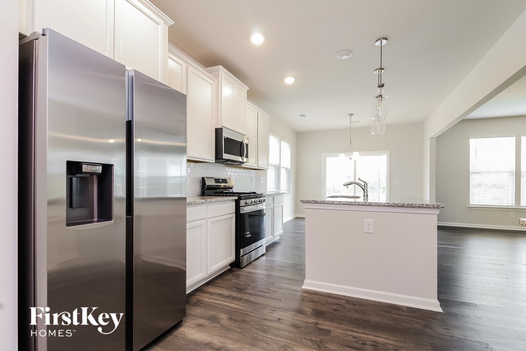 A modern kitchen with a stainless steel refrigerator and wooden floors.