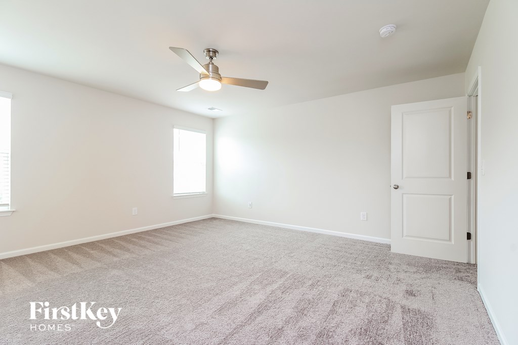 A spacious room with a ceiling fan and carpeted floor.