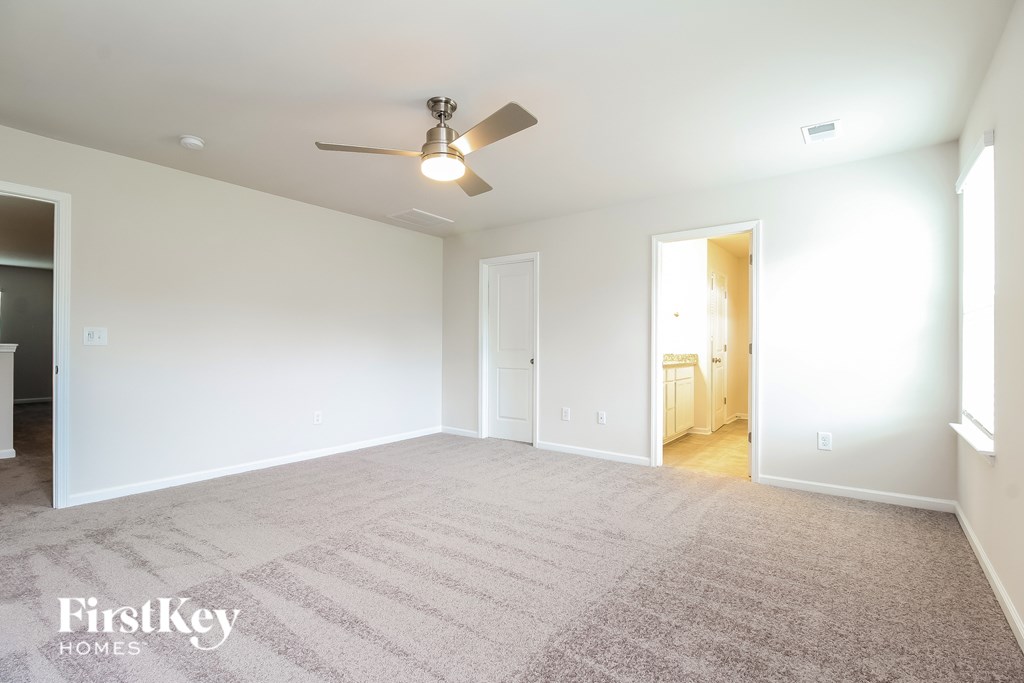 A spacious room with a carpeted floor and a ceiling fan.