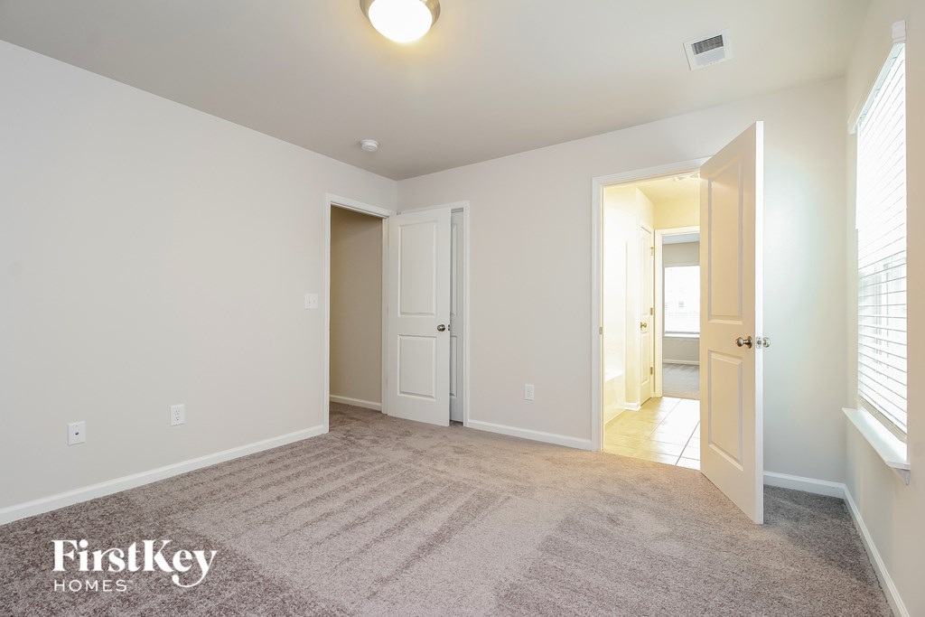 A carpeted room with a doorway leading to another room.