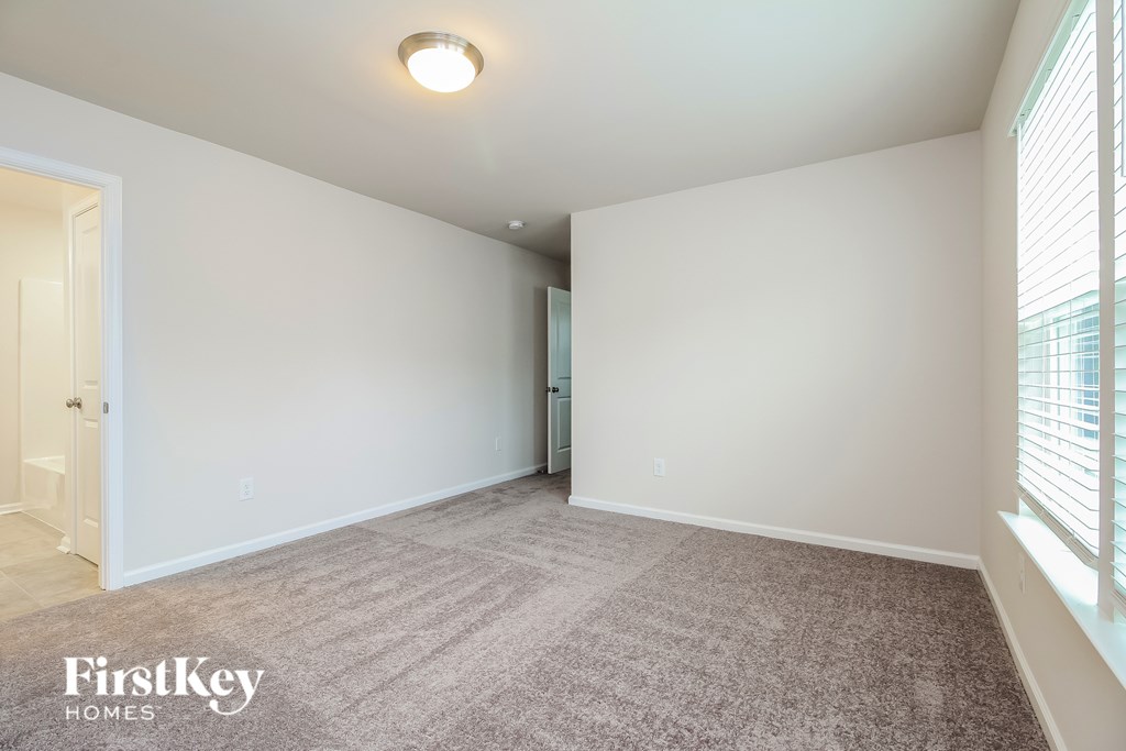 A room with a carpeted floor and a window with blinds.