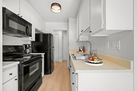 a renovated kitchen with black appliances and white cabinets