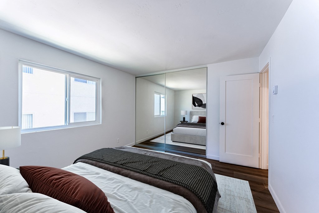 a bedroom with a large bed and a mirror in the middle