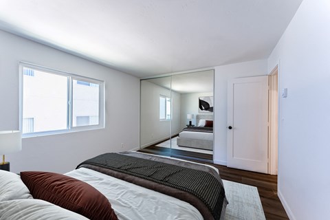 a bedroom with a large bed and a mirror in the middle