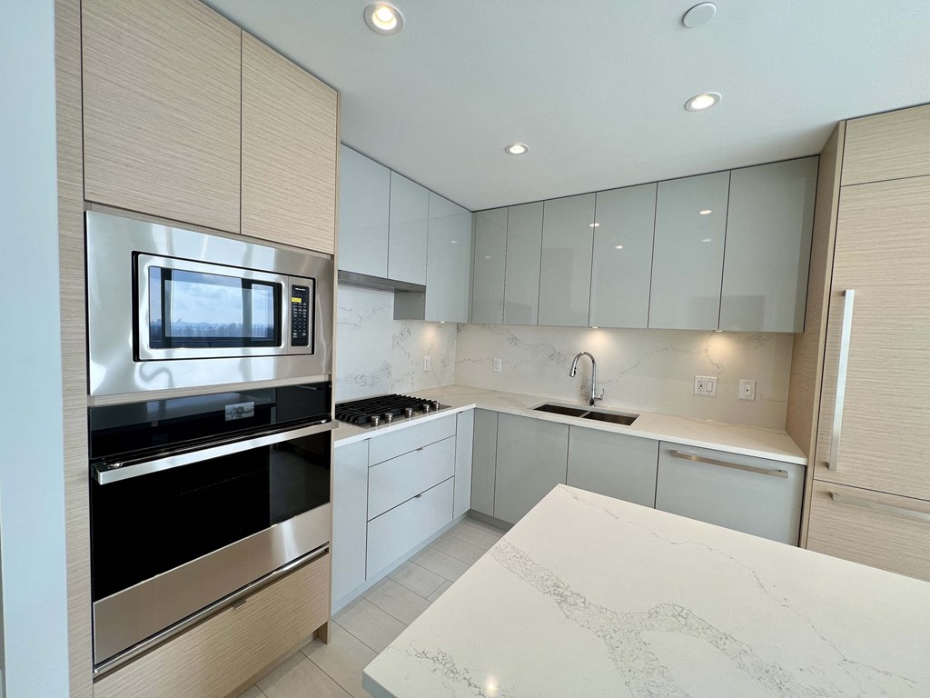 A modern kitchen with a white countertop and stainless steel appliances.