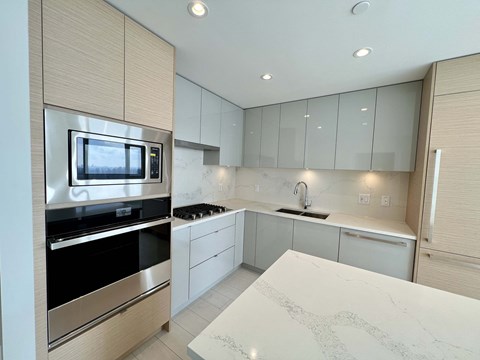 A modern kitchen with a white countertop and stainless steel appliances.