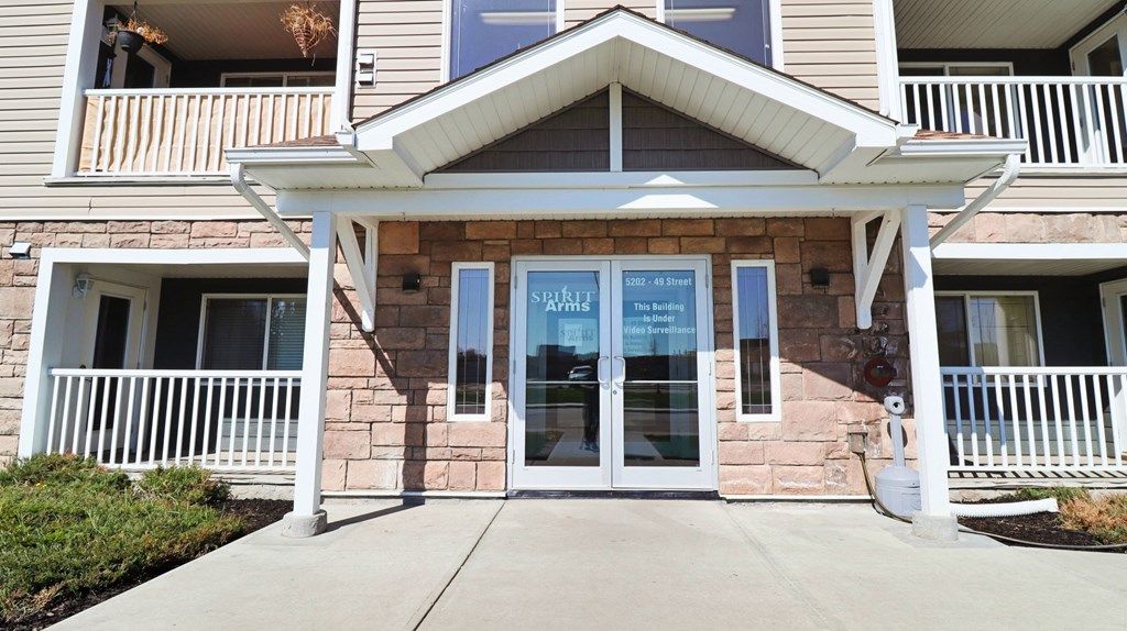 the front entrance of a building with glass doors and a porch