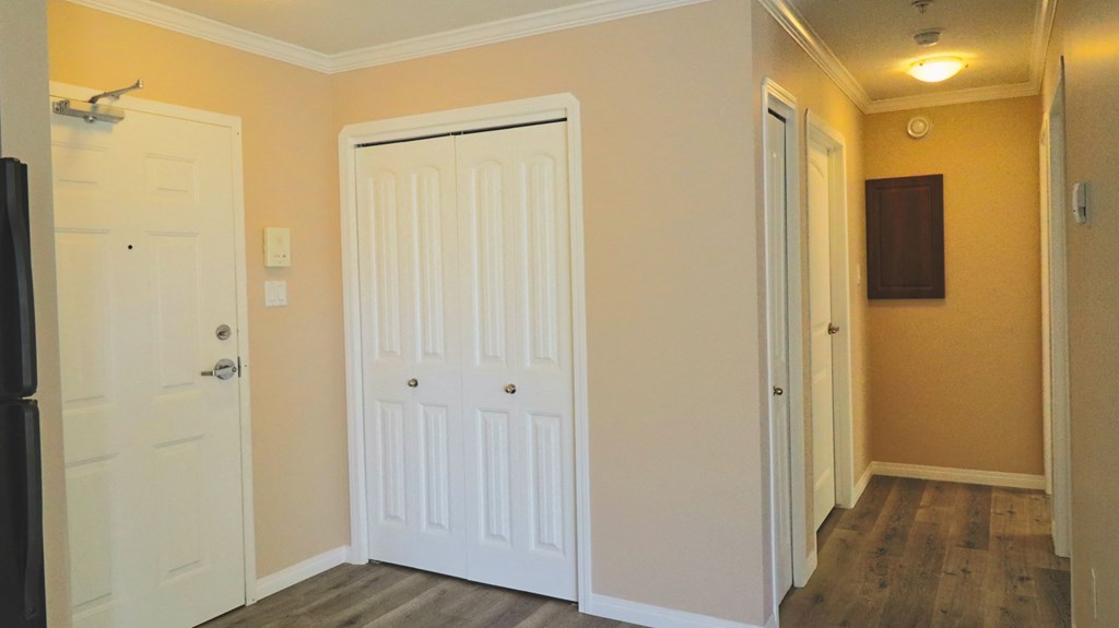 a room with two white doors and a door to a hallway with a tv