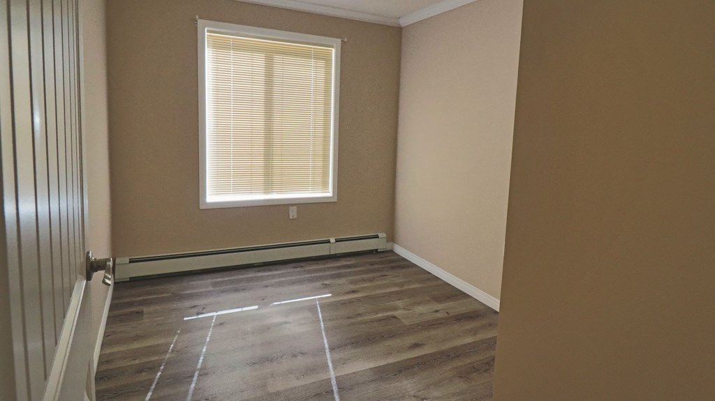 an empty room with wooden floors and a window