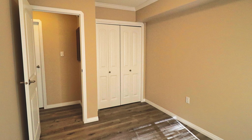 a room with wooden floors and white closet doors
