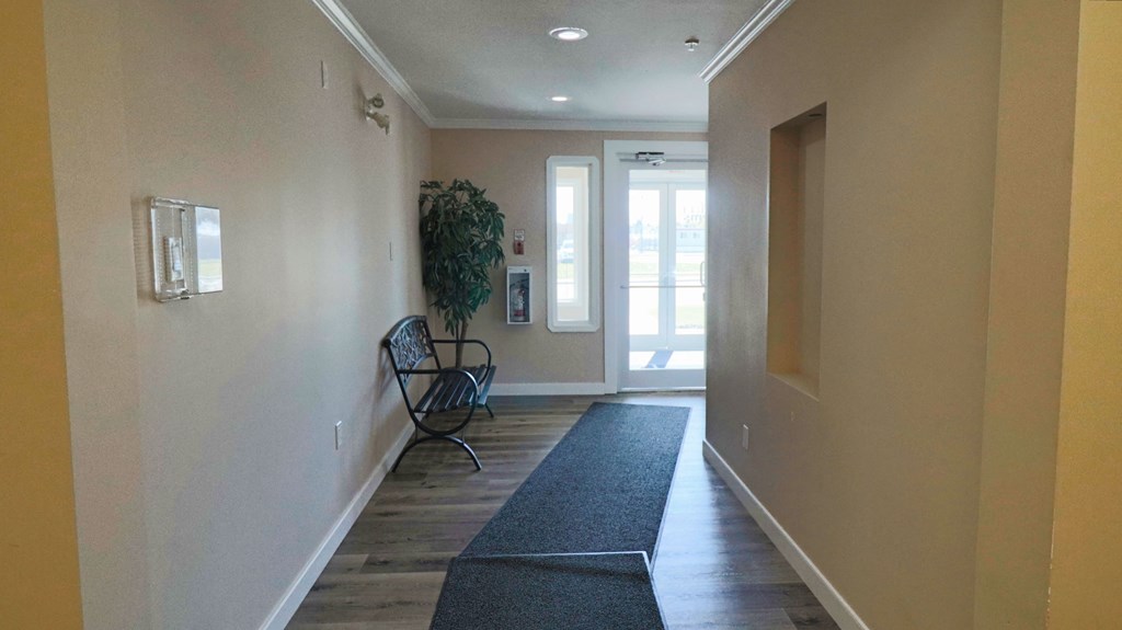 a long hallway with a chair and a rug and a door to a house