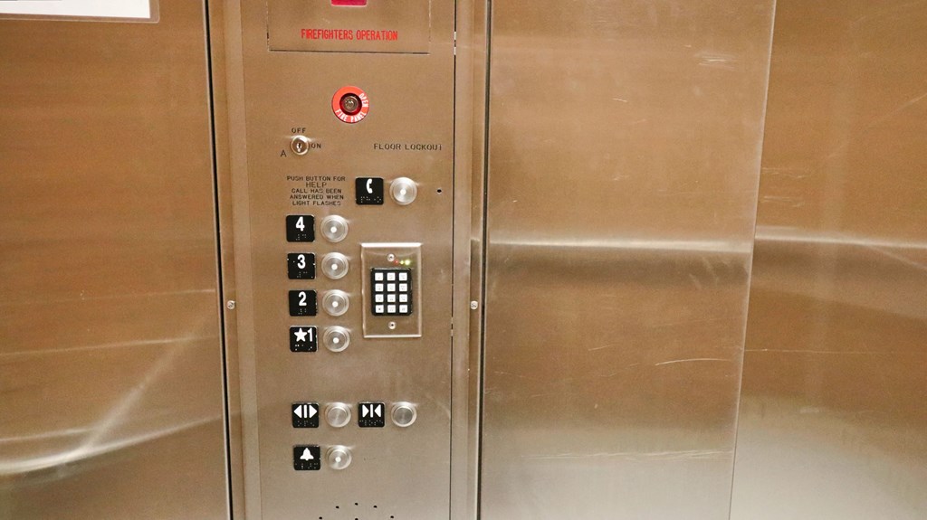 the elevator doors are stainless steel and have buttons on them