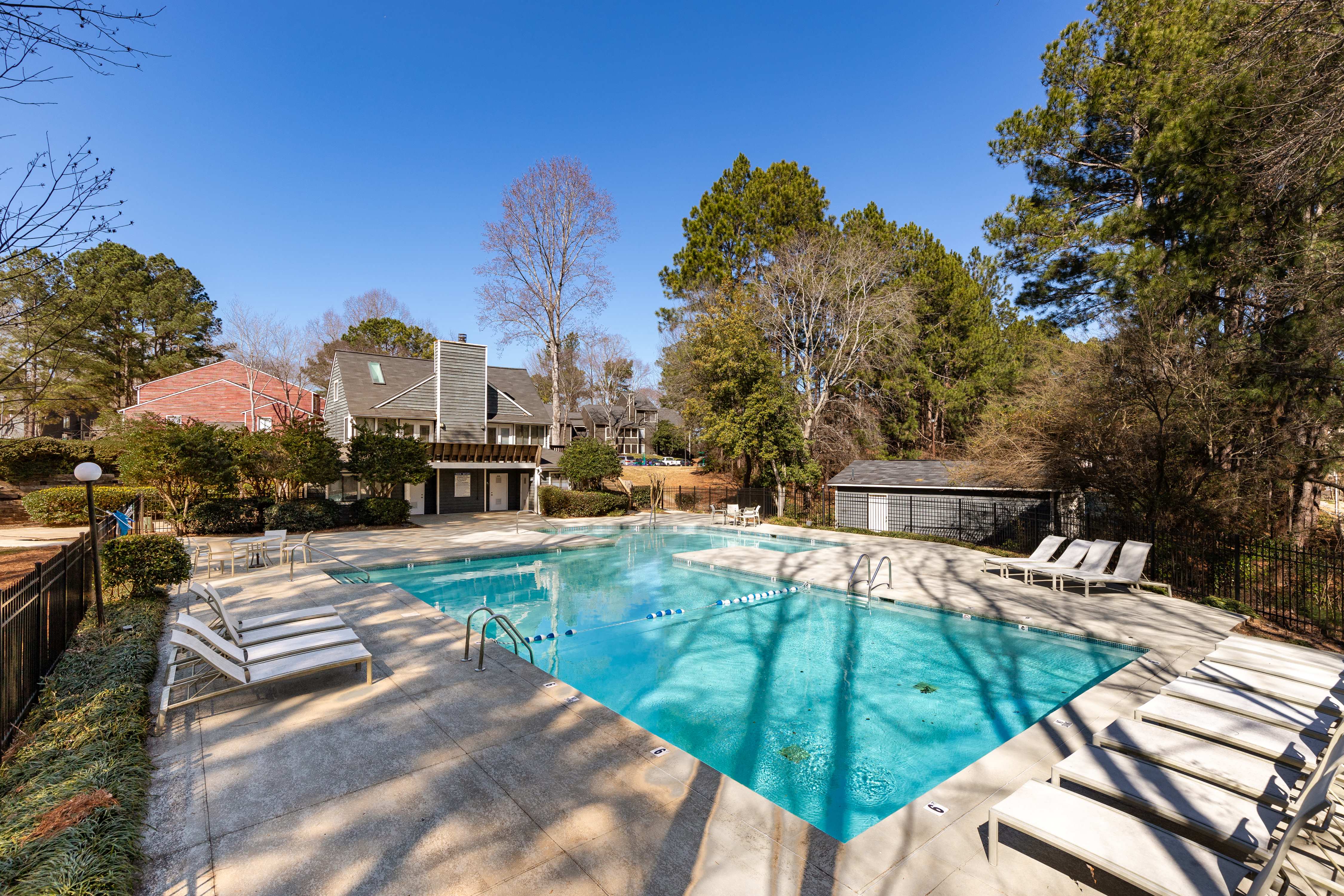 a pool with chairs and a house in the background