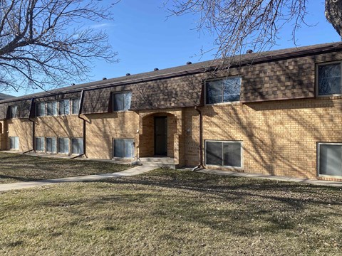 a brick building with a brown door and a grassy yard