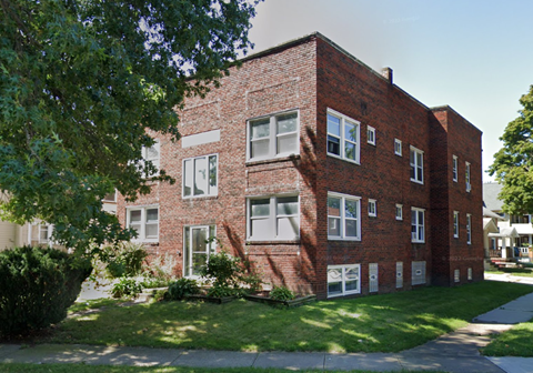 A red brick building with white windows and a green lawn in front.